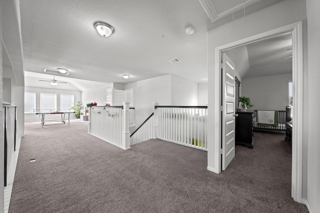 hallway with attic access, carpet flooring, visible vents, and an upstairs landing