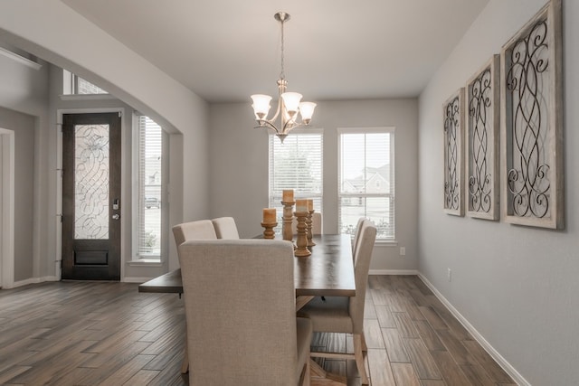 dining area featuring arched walkways, plenty of natural light, dark wood finished floors, and baseboards