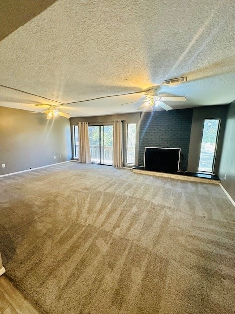 unfurnished living room with carpet floors, a textured ceiling, and a wealth of natural light