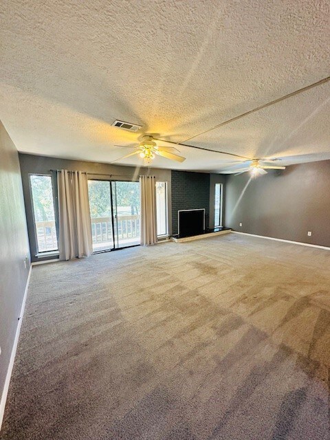 unfurnished living room featuring a large fireplace, carpet floors, and a textured ceiling