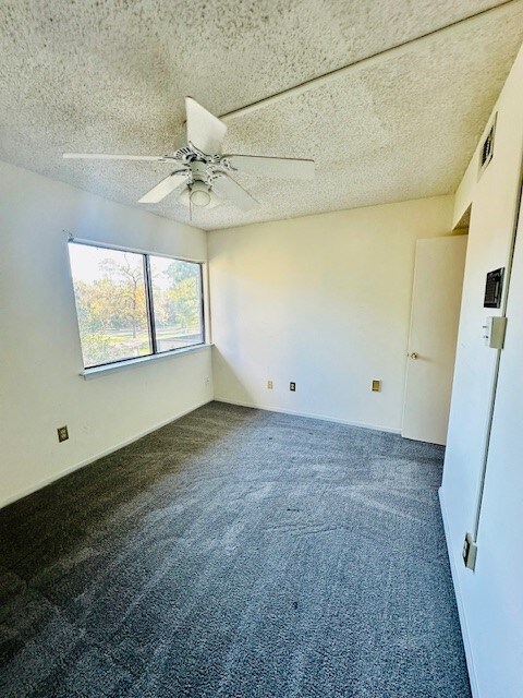 spare room with dark colored carpet, a textured ceiling, and ceiling fan