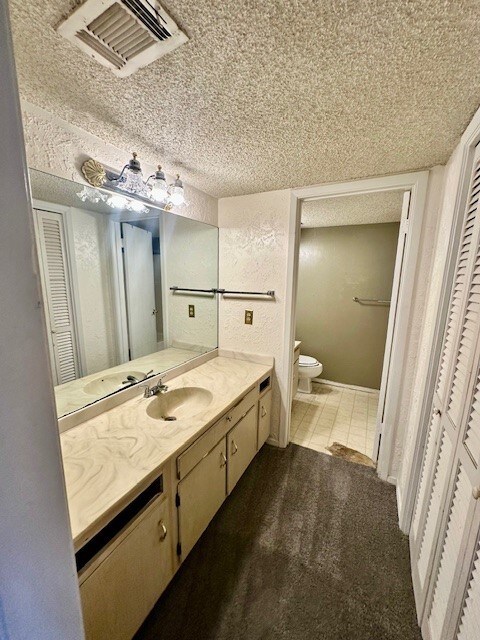 bathroom with tile patterned floors, vanity, toilet, and a textured ceiling