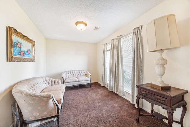 sitting room featuring a textured ceiling and dark colored carpet