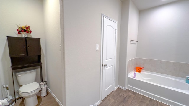 bathroom featuring a washtub, toilet, and hardwood / wood-style flooring