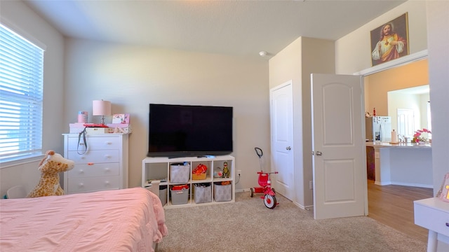 bedroom with light carpet and white fridge with ice dispenser