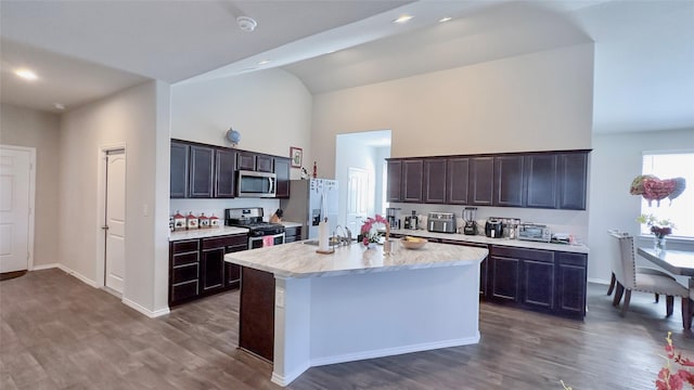 kitchen featuring dark brown cabinetry, stainless steel appliances, dark wood-type flooring, and an island with sink