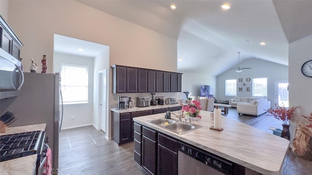 kitchen featuring sink, stainless steel appliances, dark hardwood / wood-style flooring, vaulted ceiling, and a kitchen island with sink