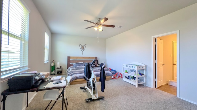 bedroom with light colored carpet, ensuite bath, and ceiling fan