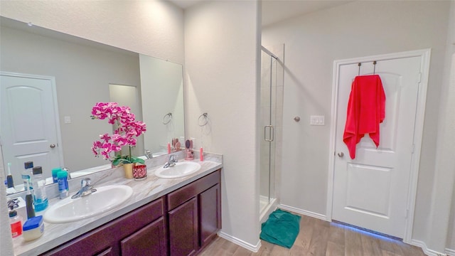 bathroom with wood-type flooring, vanity, and an enclosed shower