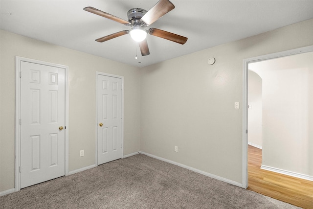 unfurnished bedroom featuring ceiling fan, carpet floors, and two closets