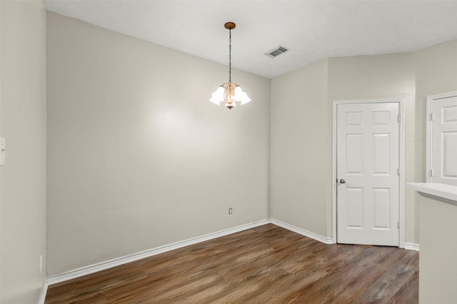 empty room featuring dark hardwood / wood-style flooring and a chandelier