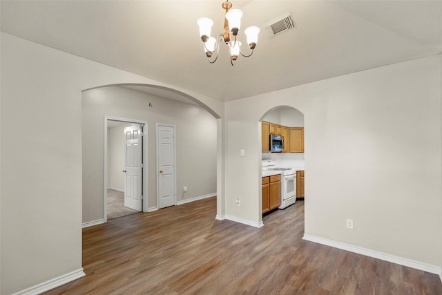 unfurnished room with wood-type flooring and a notable chandelier