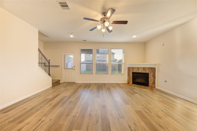 unfurnished living room with ceiling fan, a fireplace, and light hardwood / wood-style flooring