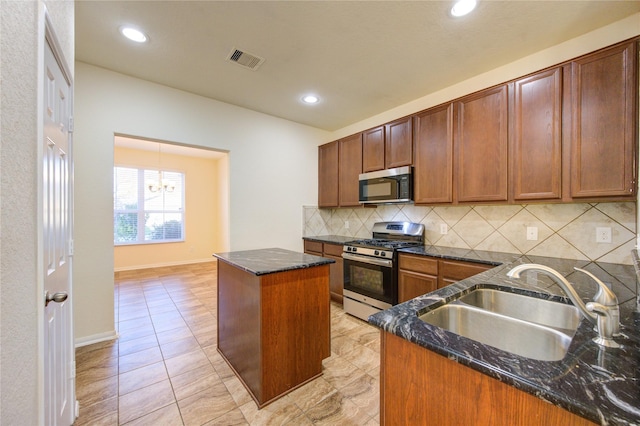 kitchen featuring sink, a center island, dark stone counters, and appliances with stainless steel finishes