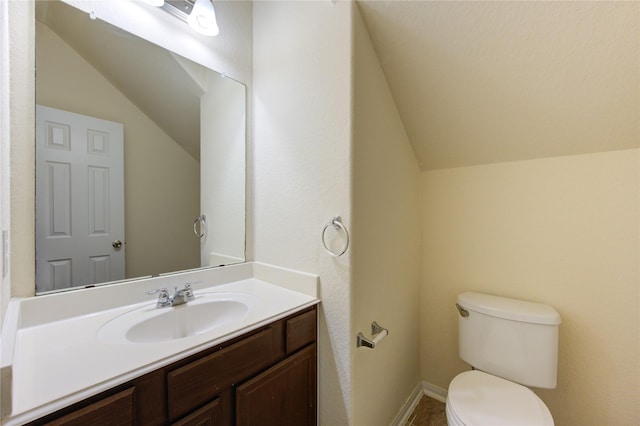 bathroom with toilet, vanity, and vaulted ceiling