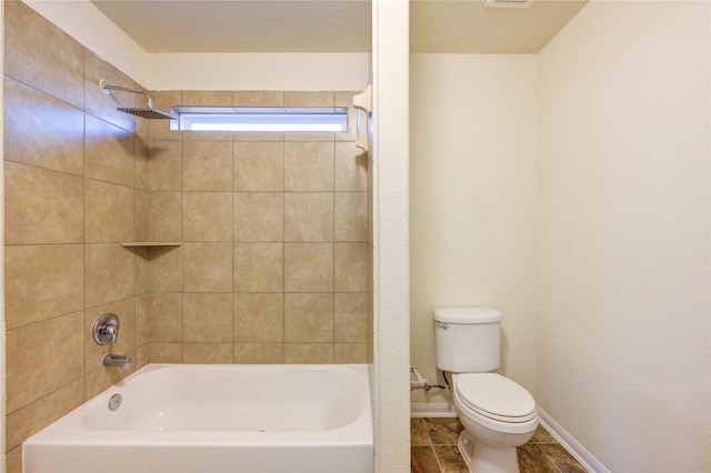 bathroom with tile patterned flooring, tiled shower / bath combo, and toilet