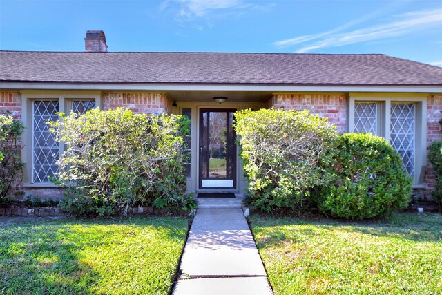 view of exterior entry with a yard