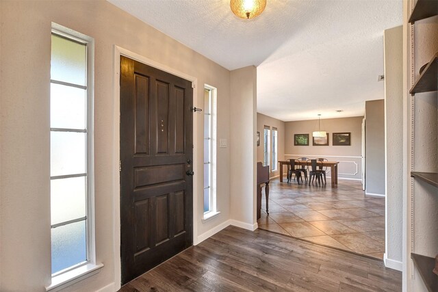 entryway with a textured ceiling, dark hardwood / wood-style flooring, and a wealth of natural light