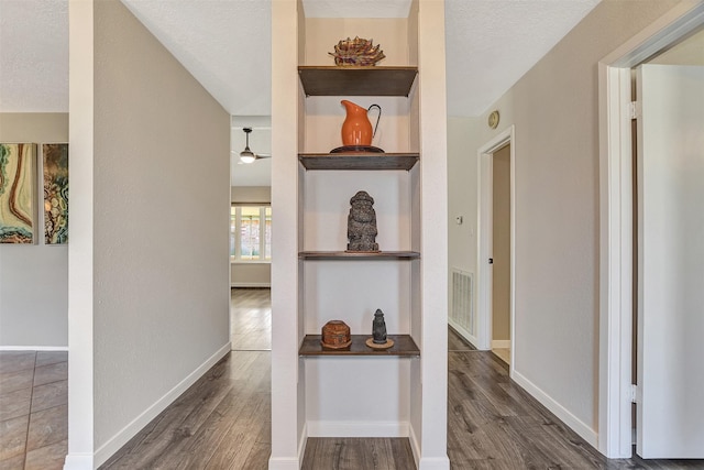 corridor featuring a textured ceiling and dark wood-type flooring