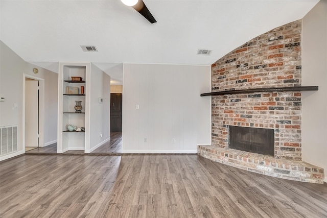 unfurnished living room featuring built in shelves, a brick fireplace, ceiling fan, and hardwood / wood-style flooring