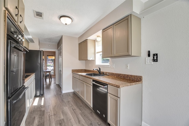 kitchen with appliances with stainless steel finishes, a textured ceiling, light hardwood / wood-style floors, and sink