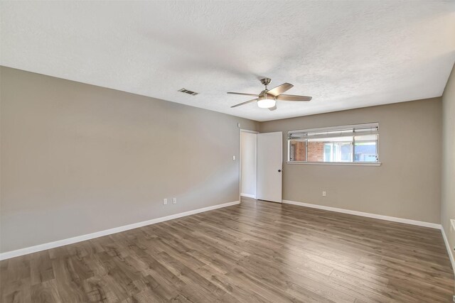 unfurnished room with ceiling fan, dark wood-type flooring, and a textured ceiling