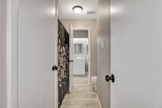 hall featuring a textured ceiling