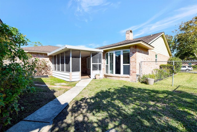 rear view of house featuring a lawn and a sunroom