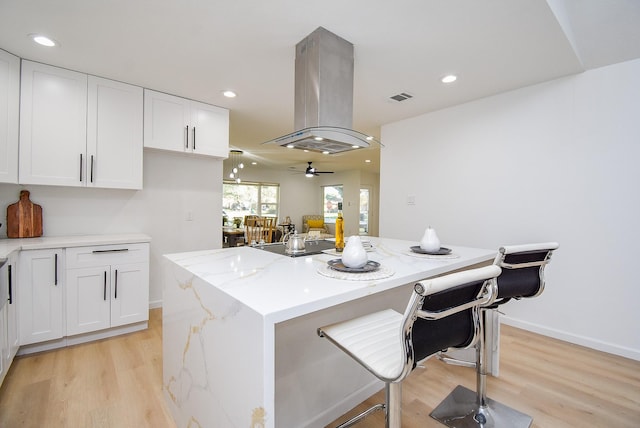 kitchen featuring island exhaust hood, a center island, white cabinetry, and ceiling fan