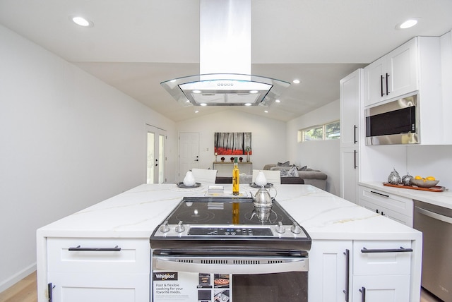 kitchen featuring lofted ceiling, light stone countertops, appliances with stainless steel finishes, white cabinetry, and island exhaust hood