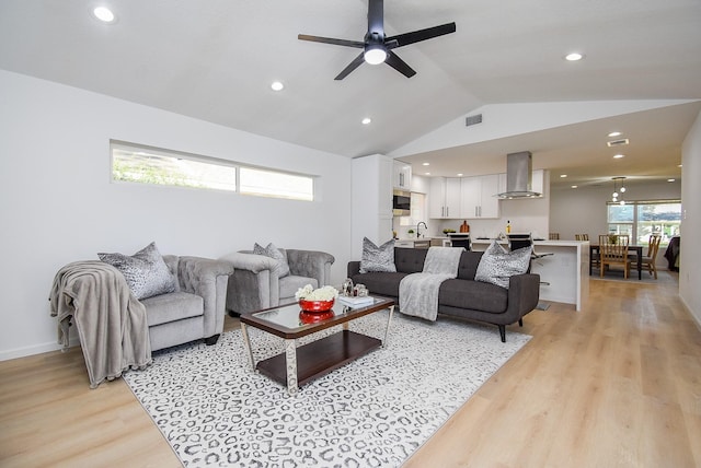 living room with light wood-type flooring, vaulted ceiling, ceiling fan, and sink