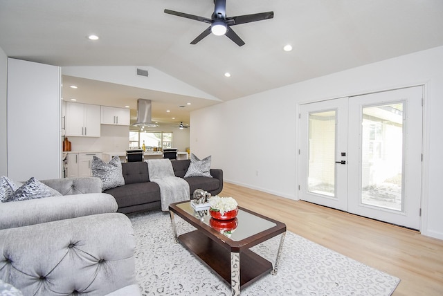 living room with ceiling fan, french doors, lofted ceiling, and light wood-type flooring