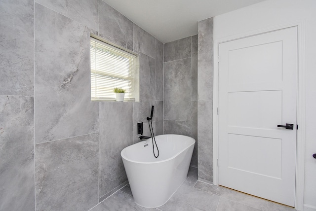 bathroom featuring tile patterned floors, a bathtub, and tile walls