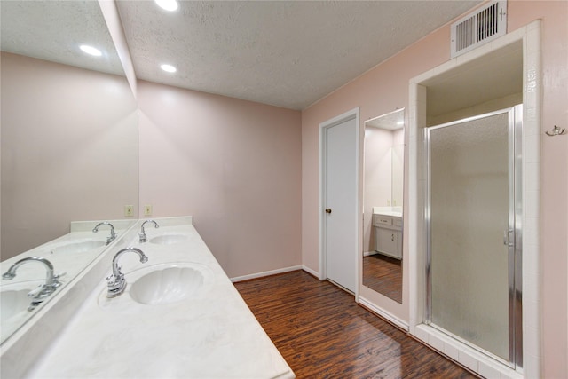 bathroom featuring vanity, a shower with door, wood-type flooring, and a textured ceiling