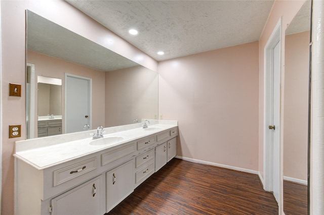 bathroom with wood-type flooring, vanity, and a textured ceiling