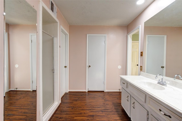 bathroom with hardwood / wood-style floors, vanity, an enclosed shower, and a textured ceiling