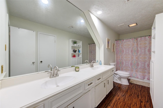 bathroom with vanity, wood-type flooring, a textured ceiling, and toilet