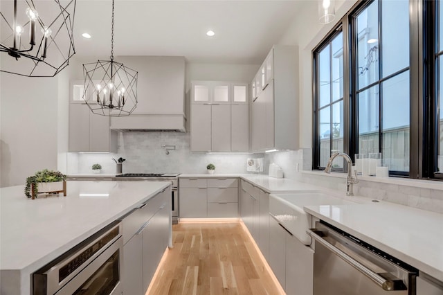 kitchen featuring white cabinetry, pendant lighting, stainless steel appliances, and light hardwood / wood-style flooring