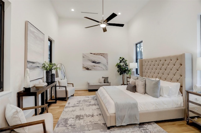 bedroom featuring light hardwood / wood-style floors, high vaulted ceiling, and ceiling fan