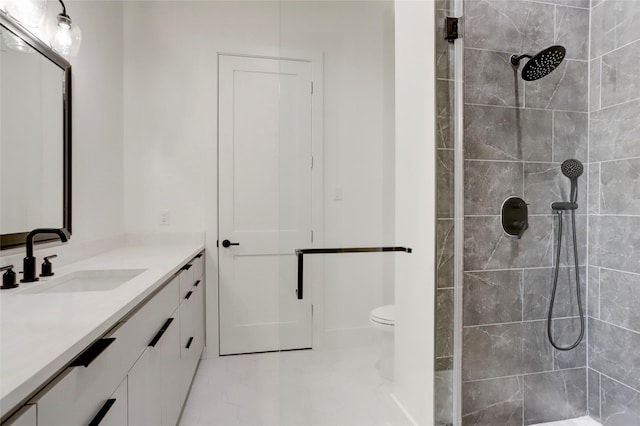 bathroom with tiled shower, vanity, and toilet