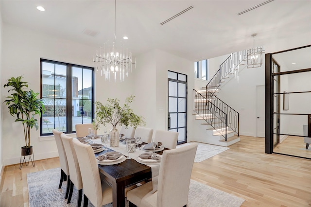 dining space with a notable chandelier, plenty of natural light, and light wood-type flooring