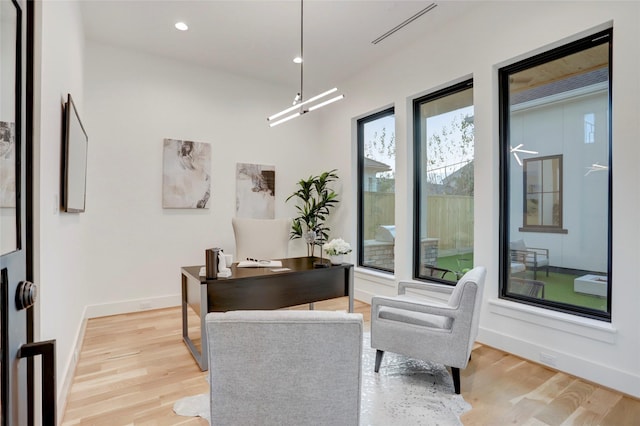 office area with light hardwood / wood-style floors and an inviting chandelier