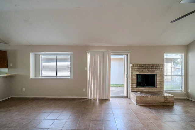 unfurnished living room with ceiling fan, a fireplace, and light tile patterned floors