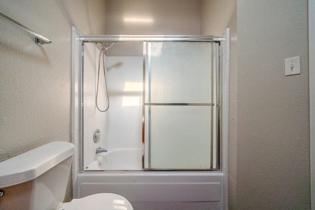 bathroom featuring combined bath / shower with glass door and toilet