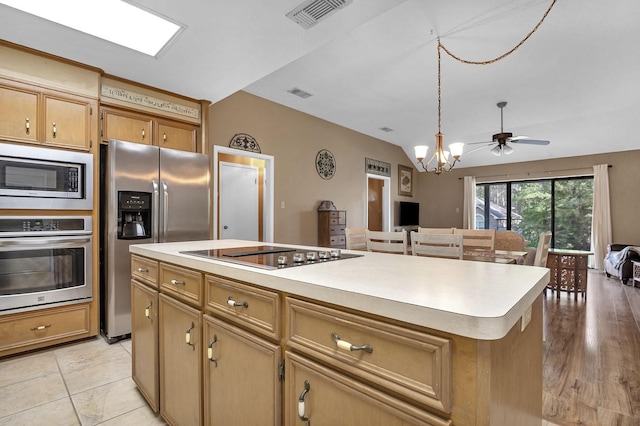 kitchen featuring ceiling fan with notable chandelier, stainless steel appliances, light hardwood / wood-style floors, a kitchen island, and lofted ceiling