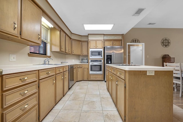 kitchen featuring a skylight, a center island, sink, stainless steel appliances, and light tile patterned flooring