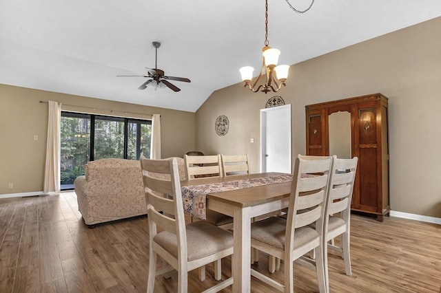 dining area with hardwood / wood-style flooring, ceiling fan with notable chandelier, and vaulted ceiling