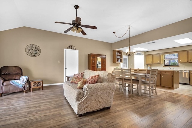 living room featuring hardwood / wood-style floors, ceiling fan with notable chandelier, sink, and vaulted ceiling