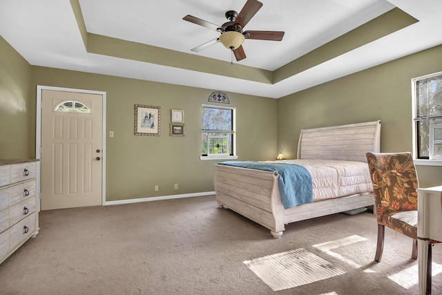 bedroom with light carpet, a tray ceiling, and ceiling fan