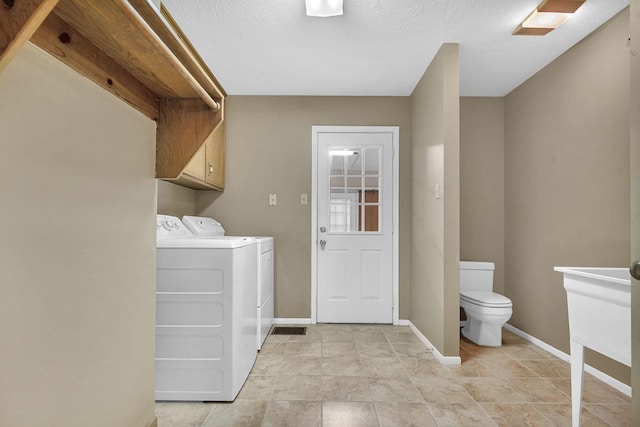 clothes washing area with washer and dryer and a textured ceiling